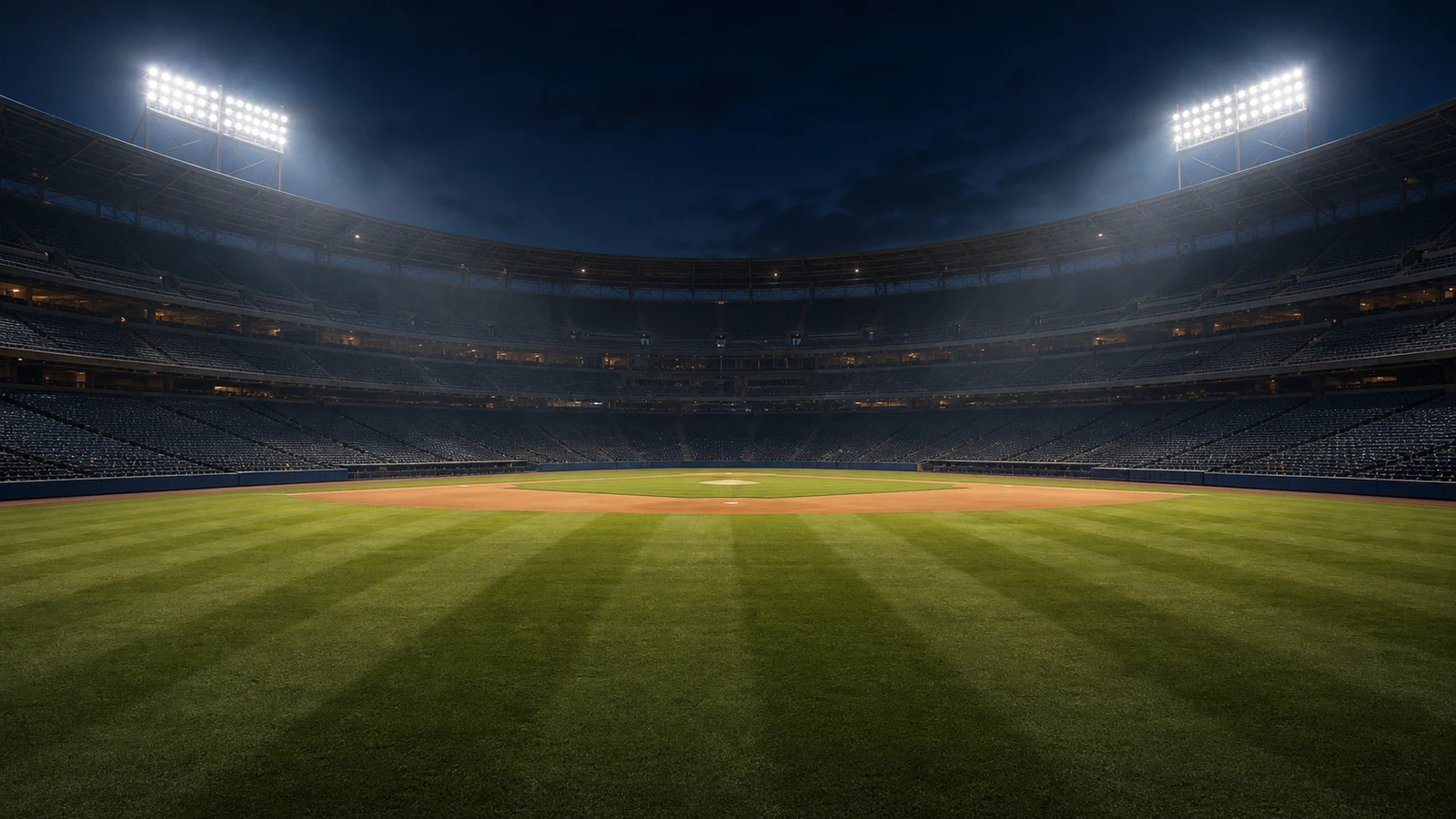 An empty baseball stadium under lights at night.